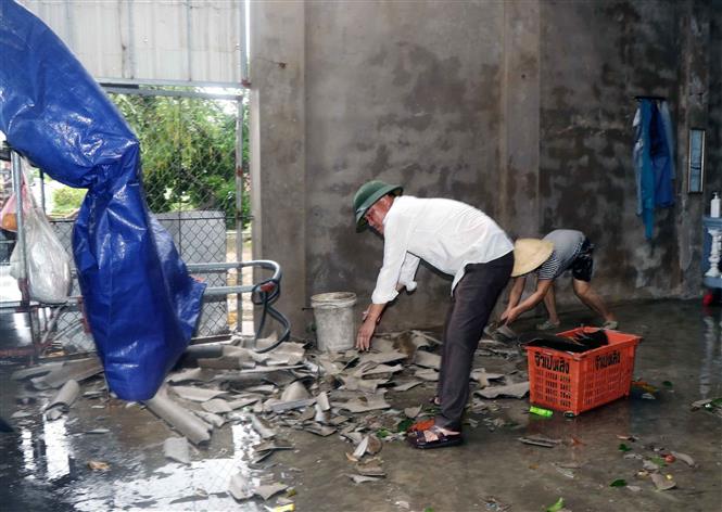 Vợ chồng anh Lê Đình Hùng, thôn Quang Trung xã Thịnh Lộc huyện Lộc Hà đang dọn dẹp mái ngói do lốc xoáy gây ra. Ảnh: Công Tường-TTXVN
